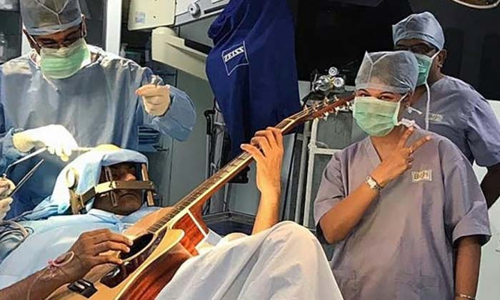 индиец играет на гитаре во время операции на мозге